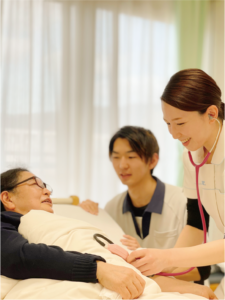 職員が入居者と食事をサポートしている様子。食卓での介護場面。
